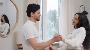 Bir çift, pencerenin yanında dururken içten bir etkileşimden zevk alır..