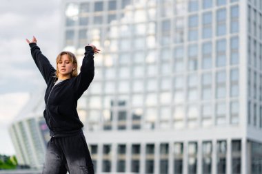 Bir dansçı yeteneklerini modern bir şehrin gökyüzüne karşı sergiliyor..