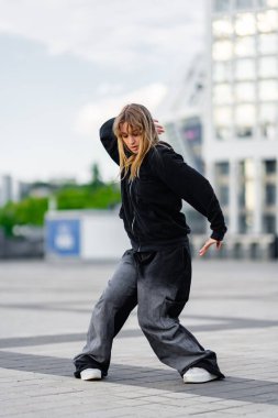 Bir dansçı, modern bir açık hava meydanında çalışırken yeteneklerini sergiler..