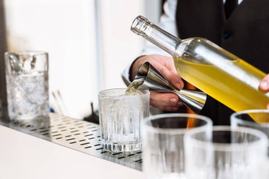 Bir barmen ustalıkla bardağa renkli bir kokteyl doldurur..