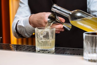 Yetenekli bir barmen bir tatma etkinliğinde bardağa kokteyl doldurur..