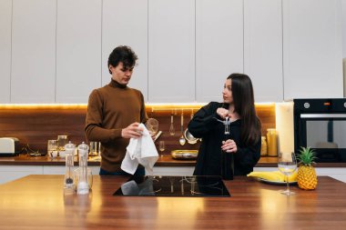 Bir çift şık bir mutfak tezgahında içkileri sıcak ışıkla karıştırıyor..