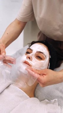 Sakinleştirici bir yüz bakımı spa 'da rahatlatıcı bir maskeden hoşlanan bir kadın içerir..
