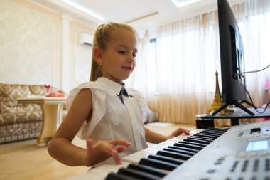 Bir kız rahat oturma odasında klavye çalmaktan hoşlanır..