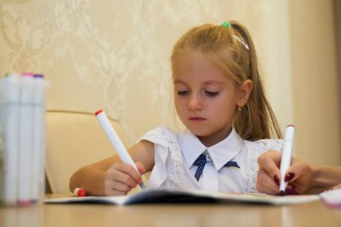 Bir çocuk, parlak kalemler ve kağıtlarla çizim yaparken konsantre olur.