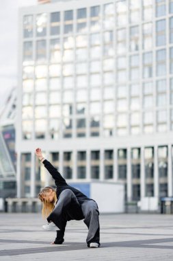 Bir dansçı modern mimari ile kentsel alanda zarif bir hareket gerçekleştirir..