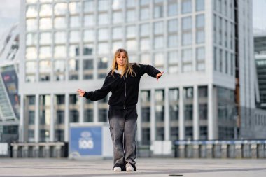 Genç bir kadın dans yeteneklerini canlı bir şehir ortamında, çatıda sergiliyor..