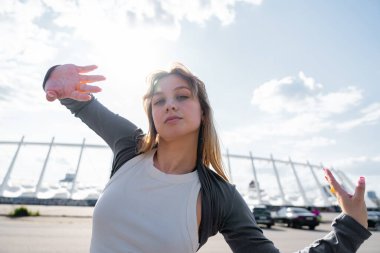 Bir dansçı dinamik bir poz verir açık hava güneşli bir yerde parlak bir arkaplan ile.