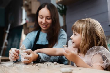 Anne ve kızı birlikte kil figürler yaratıyor, gülüşlerini ve neşelerini paylaşıyorlar..