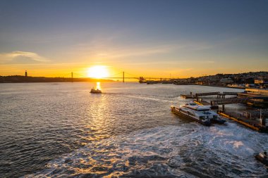 Gün batımında bir tekne nehrin karşısına geçer, ufku ve şehri aydınlatır..