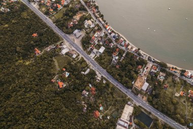 Gün batımında evler, yollar ve yemyeşil yemyeşil verimli kıyı manzarası.