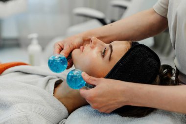 Relaxation and skincare come together as a woman enjoys a facial treatment with gel balls. clipart