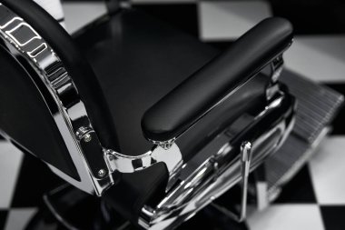 Pürüzsüz, krom renkli berber koltuğu damalı döşemeleri olan şık bir salonda müşteriyi bekliyor..