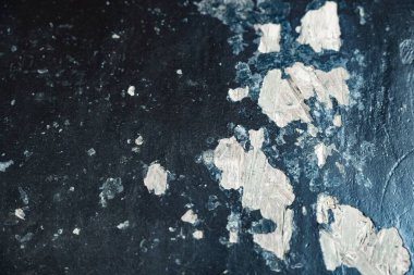 Close view of a textured surface showing peeling paint in various shades against a dark backdrop. clipart