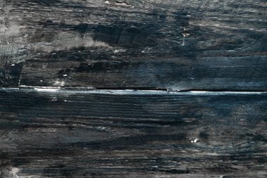 Yıpranmış ahşap bir yüzeye yakın plan zengin dokular ve çatlaklı koyu renkler sergiliyor.