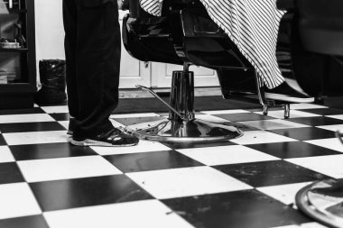 Şık bir berber koltuğunda oturan müşteri saçını kestiriyor..