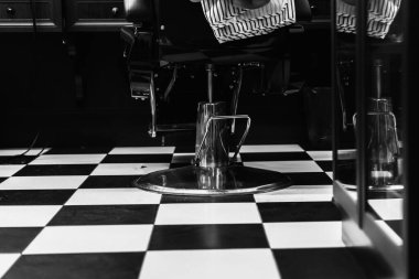 Kareli zemini olan şık bir berber dükkanı ve modern bir sandalye müşteriyi bekliyor..