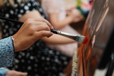 Sanat dersinde yaratıcılık akarken bir el fırçayı tutar..