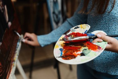 Bir insan resim yaparken parlak renkleri karıştırıyor.