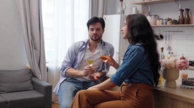 Bir çift, rahat bir evde kahkaha ve içki paylaşıyor..