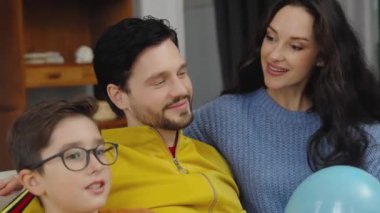 Bir aile evde balonlarla oynarken gülümseme ve kahkaha paylaşır..