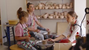 Eğitmenler çömlek parçalarını bir araya getirmede iki öğrenciye rehberlik ediyor..