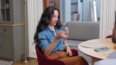 Bir kadın elinde bir kadeh şarap tutarken keyifli bir sohbetten hoşlanır..