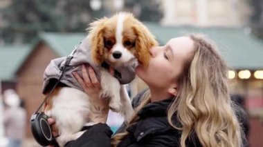 Bir kadın, canlı bir atmosferde küçük köpeğini kucaklıyor..