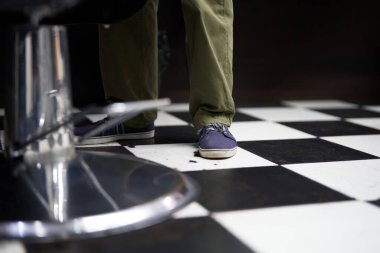 Bir berber dükkanında, siyah beyaz bir zeminde dinlenen bir insan.