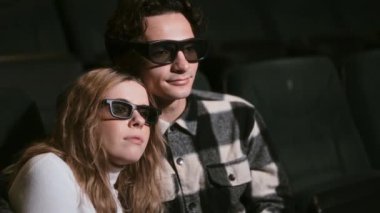 Çift tiyatroda birbirine yakın oturuyor ve 3D gözlük takıyor..