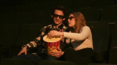 Bir çift loş bir sinemada film izlerken patlamış mısır paylaşır..