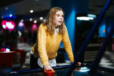 Genç bir kadın hareketli bir oyun salonunda hokey oynarken konsantre oluyor..