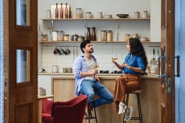 Modern bir mutfakta içkileri paylaşan iki arkadaş rahatlar ve sohbet ederler..