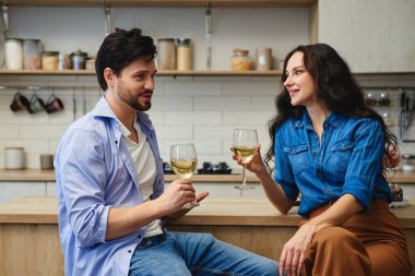Bir çift, mutfakta birlikte şarap içerken keyifli bir anı paylaşıyor..