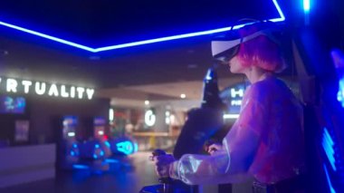 Kullanıcı, çağdaş bir eğlence merkezinde heyecan verici bir sanal gerçeklik seansından hoşlanıyor. Parlak atmosfer neon ışıklar ve son teknoloji ekipmanlarla güçlendiriliyor..