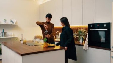 Bir çift modern mutfaklarında yemek hazırlıyor ve bir anlık neşe paylaşıyorlar..
