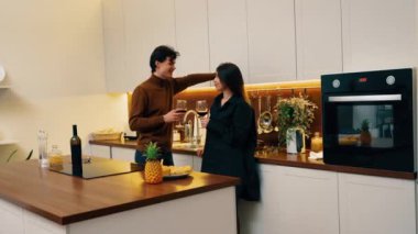 Bir çift romantik bir anı paylaşır, sıcak mutfaklarında şarap yudumlarlar..