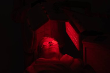 Huzurlu bir ortamda cilt yenilenmesi için kırmızı ışık tedavisi gören hasta.