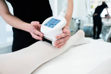 Bir teknisyen, güzellik tedavisi için bir cihazı müşterisine uygular..