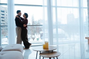 İki insan, aydınlık ve havadar bir yerde hassas bir anı paylaşıyor..