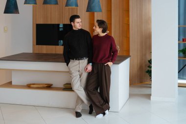 Genç çift birbirine yakın duruyor, evlerinde sevgi dolu bir anı paylaşıyorlar..