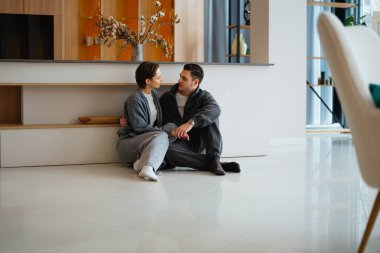 İki kişi yerde birlikte oturur, derin bir sohbete dalarlar..