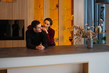 Çift, akşam saatlerinde şık bir mutfakta rahat bir anı paylaşıyor..