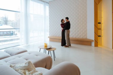 İki insan şık, parlak bir odada neşe dolu bir dansı paylaşıyor..