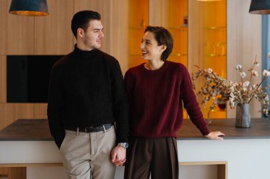 Çağdaş bir mutfakta el ele tutuşurken kadın ve erkek sıcak bir anı paylaşıyor..