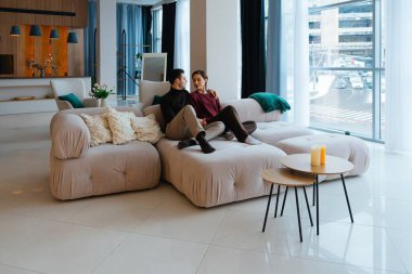 Bir çift şık bir yaşam alanında lüks bir kanepede rahatlar..