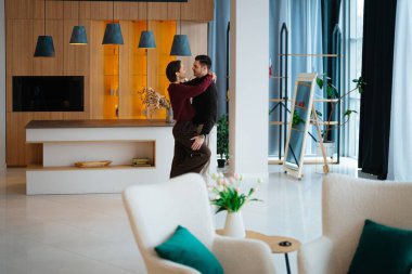 Neşeli çift şık, parlak bir oturma odasında dans ederken kucaklaşır..