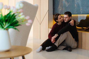 Bir çift evde şık bir şöminenin yanında yerde dinleniyor..