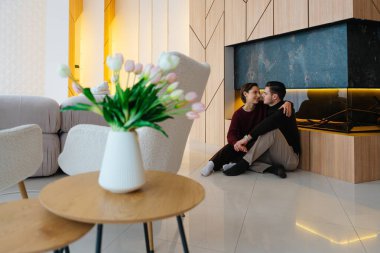 Modern bir şöminenin yanında oturan bir çift tarafından oluşturulan sıcak atmosfer.