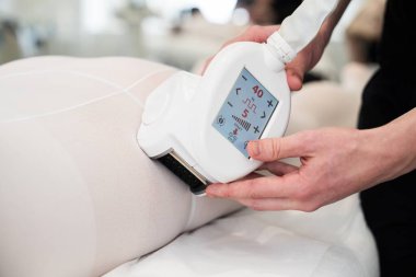 Bir terapist, özel bir cihaz kullanarak vücut hatlarını belirleyen bir tedavi uygular..